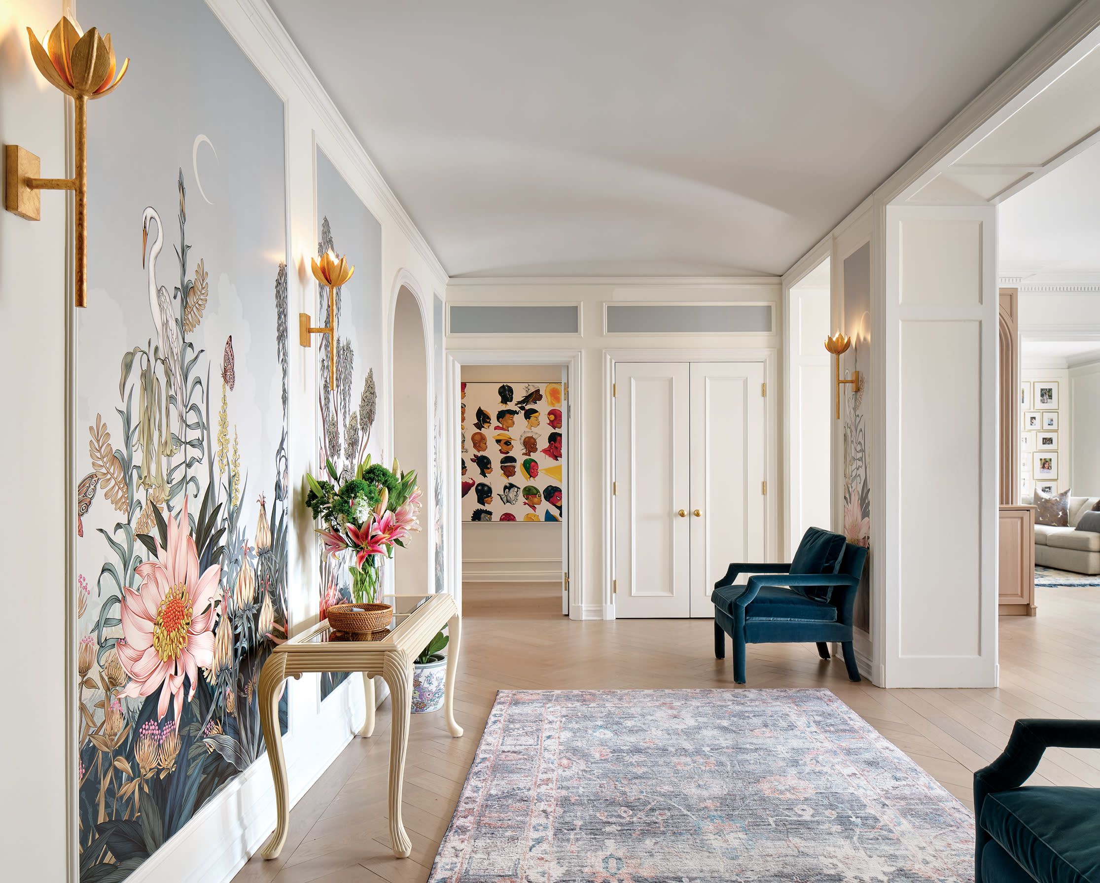 contemporary entryway with floral wallcovering, light pink and blue rug and blue armchairs