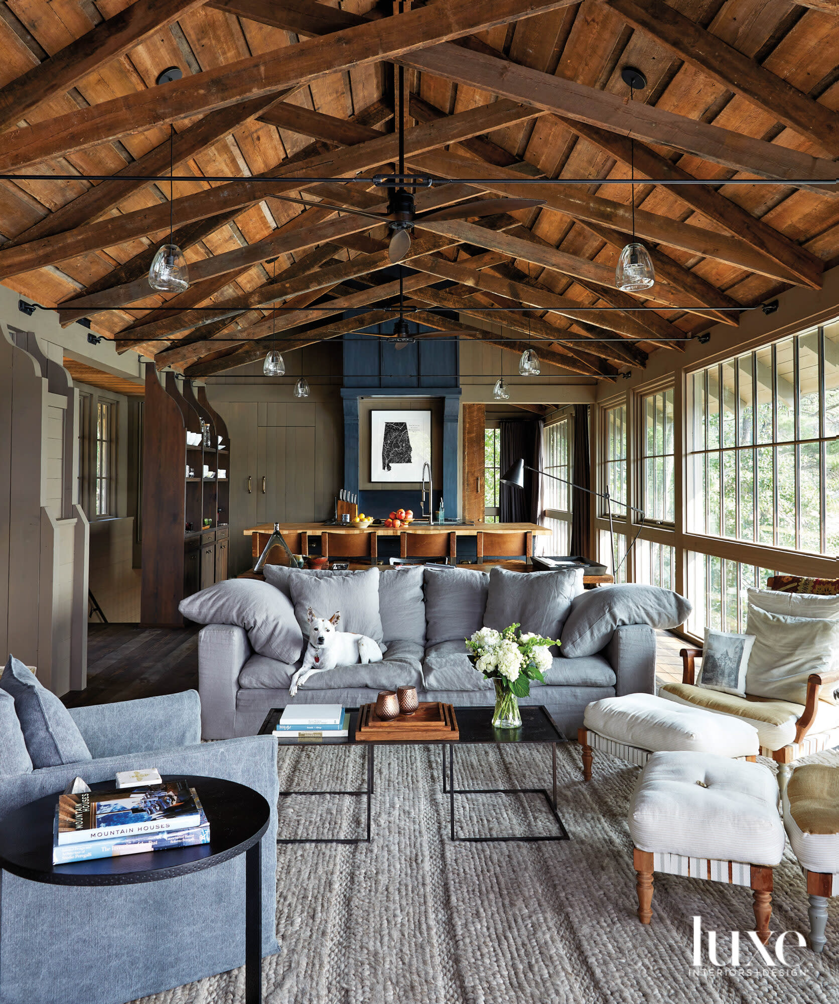 Rustic living room with exposed ceiling beams, bank of windows and comfortable seating