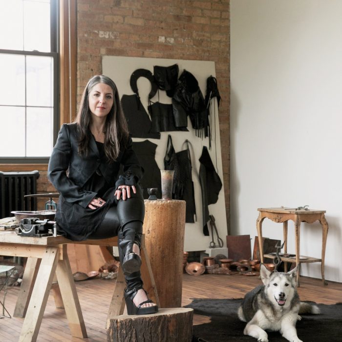 Prieto-Velasco sits with her Siberian Husky, Quinn, in her studio, which is filled with various hammers and bowls.