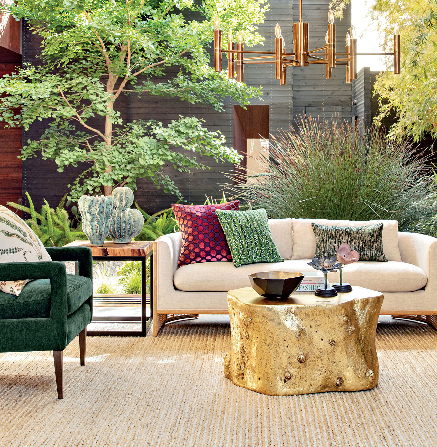 A circular table sits on a rug near a sofa with colorful throw pillows and a side table with cacti.