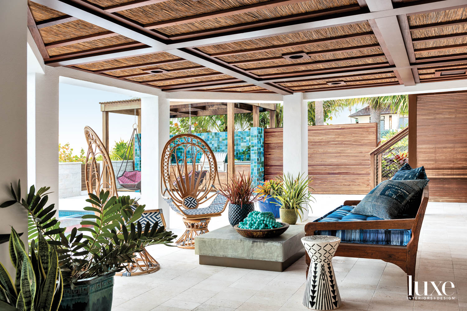 loggia with reed and ipe ceiling, travertine flooring, rattan peacock chairs, sofa and marble tables