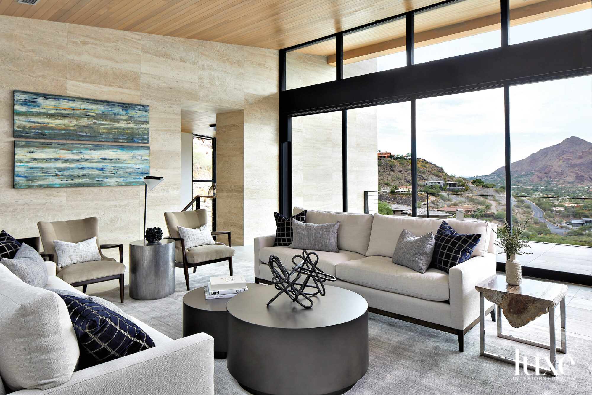 A living room with neutral sofas and an abstract painting in shades of blue by Hilario Gutierrez.