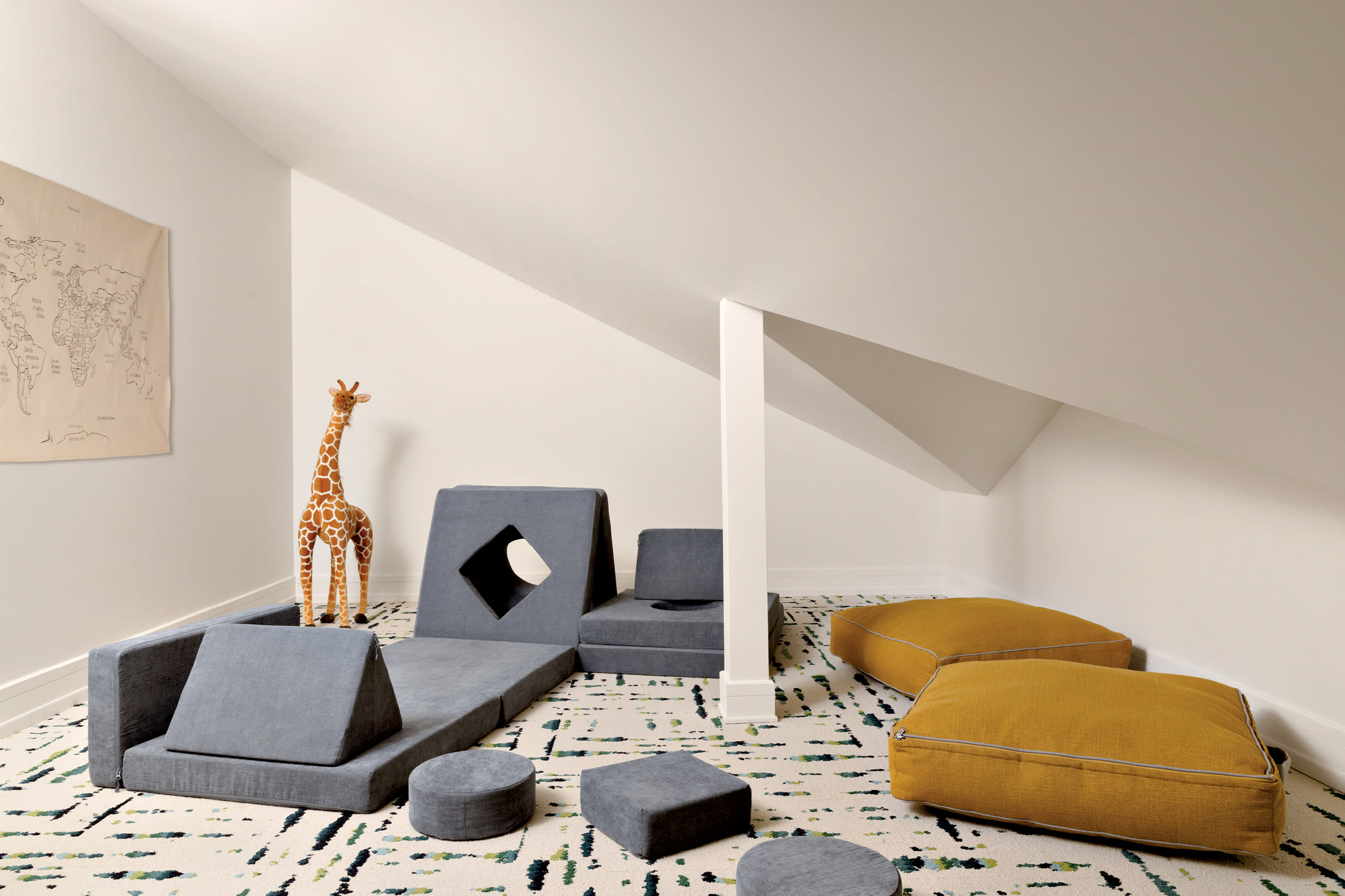 converted attic space that is now a kid's loft with floor cushions and a world map tapestry