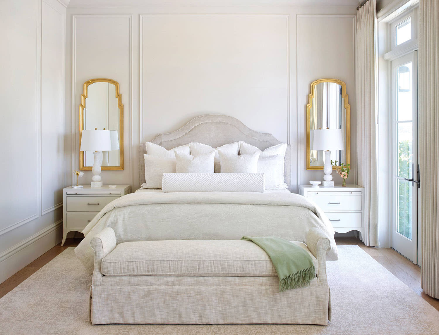 white traditional bedroom with gold-trimmed mirrors above matching nightstands