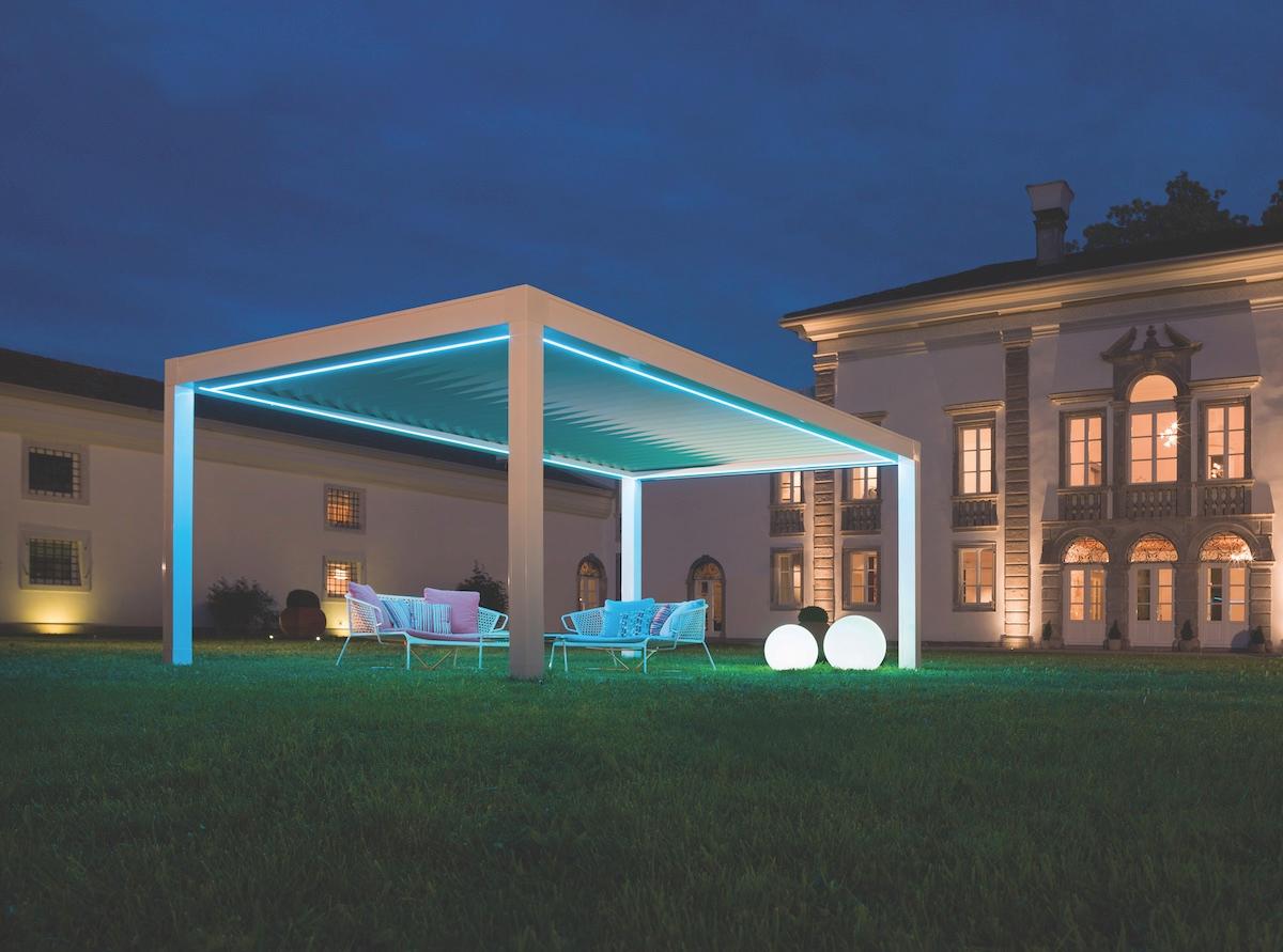 A white gazebo illuminated by blue lights, enhancing its charm in a nighttime setting.