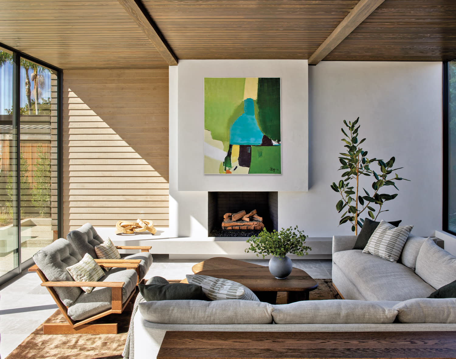 modern living room with abstract artwork hung above the fireplace, paneled wood and white walls