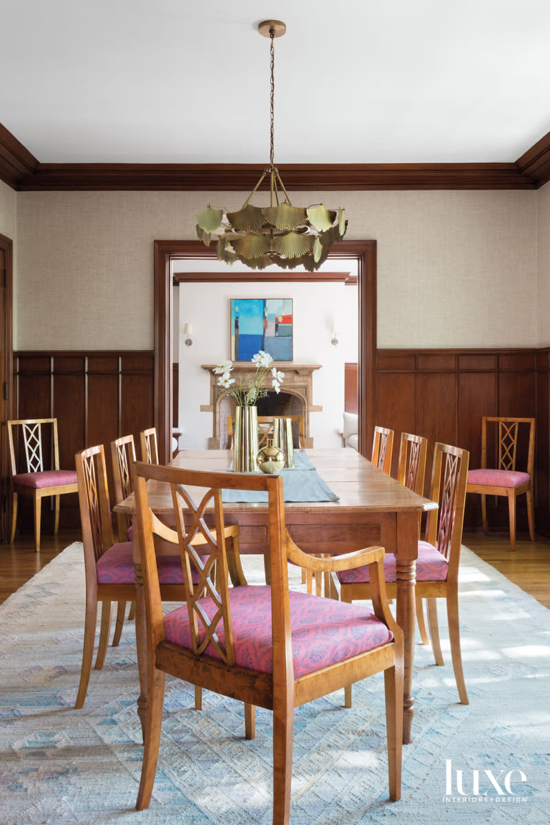 Dining room with chairs and modern light fixture above looking toward fireplace