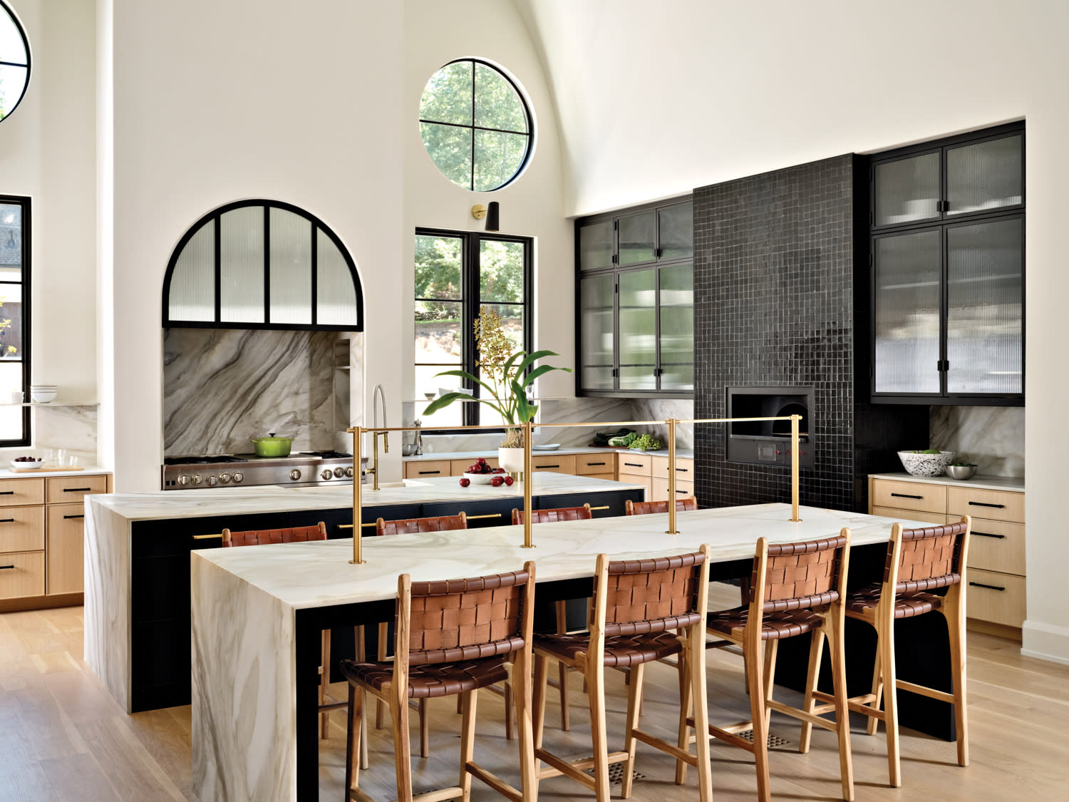 contemporary kitchen with an arched element of black metal and reeded glass over the stove hood