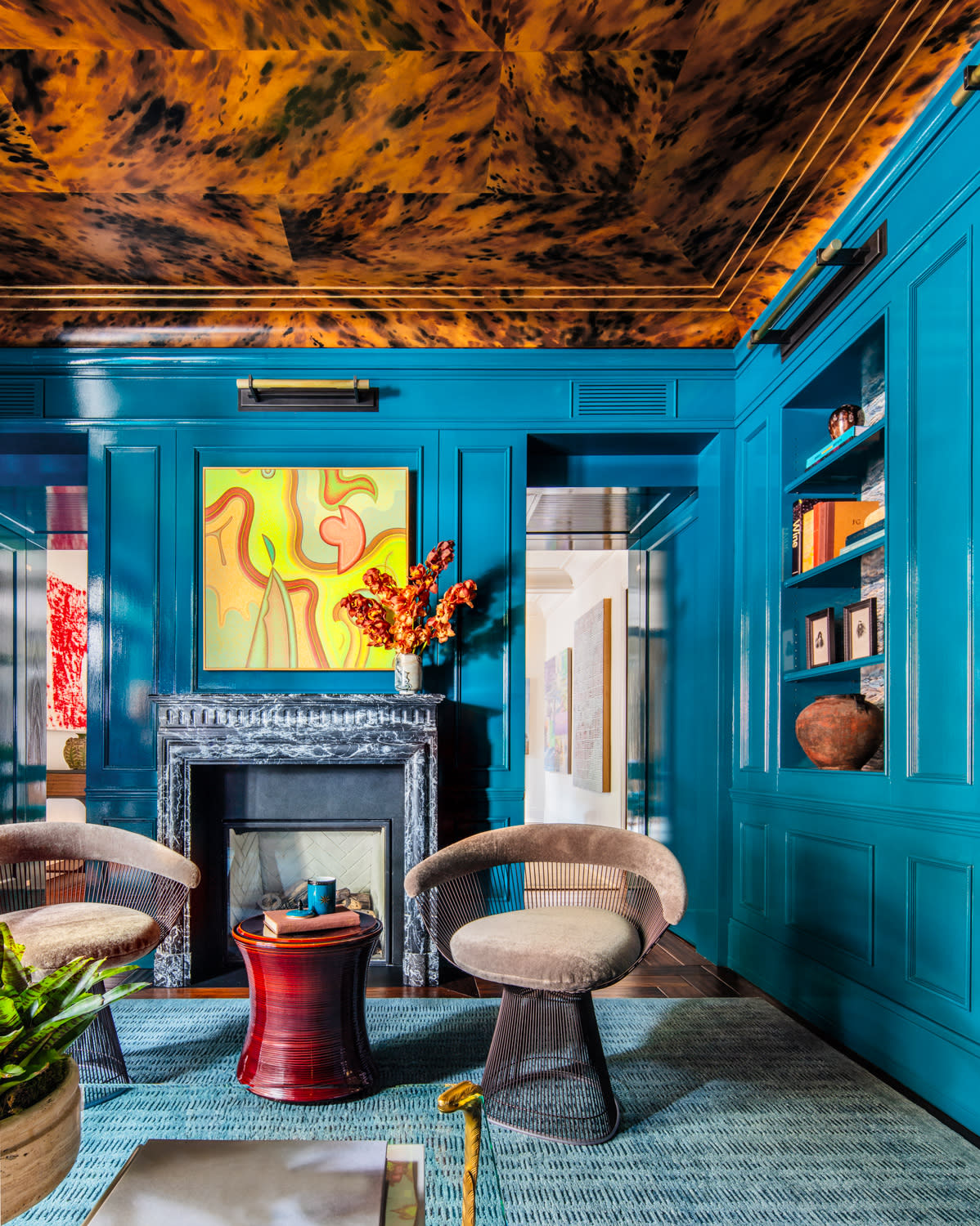 Luxurious library room with vibrant teal walls and blue carpet.
