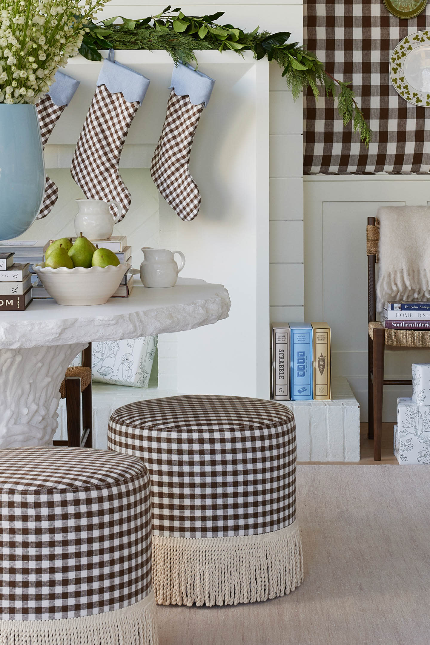 brown and white gingham ottomans below a table in front of stockings on a mantle