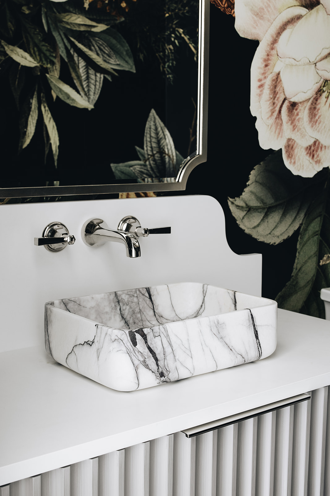 maximalist powder room with black floral wallpaper and stone sink