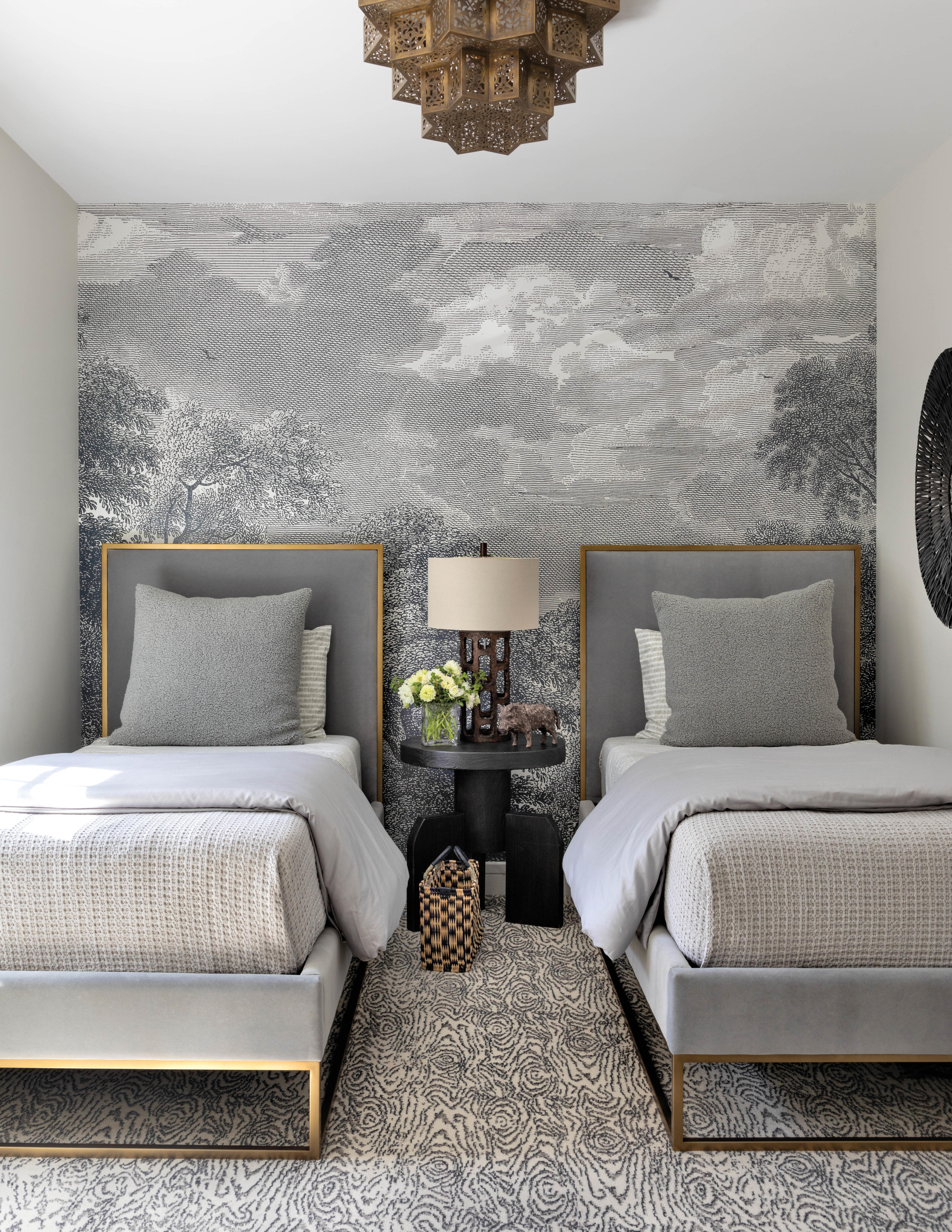 gray guest room with twin beds, cloud-like wallpaper and moroccan-inspired light fixture 