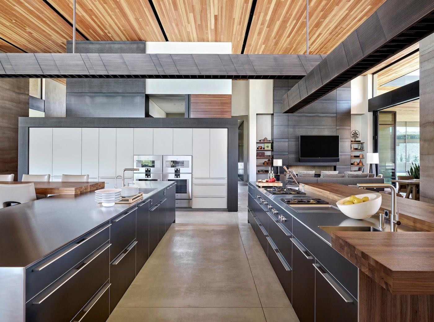 Spacious modern kitchen with sleek gray countertops, wooden accents, and high wooden ceilings. Bright, open layout with natural light.
