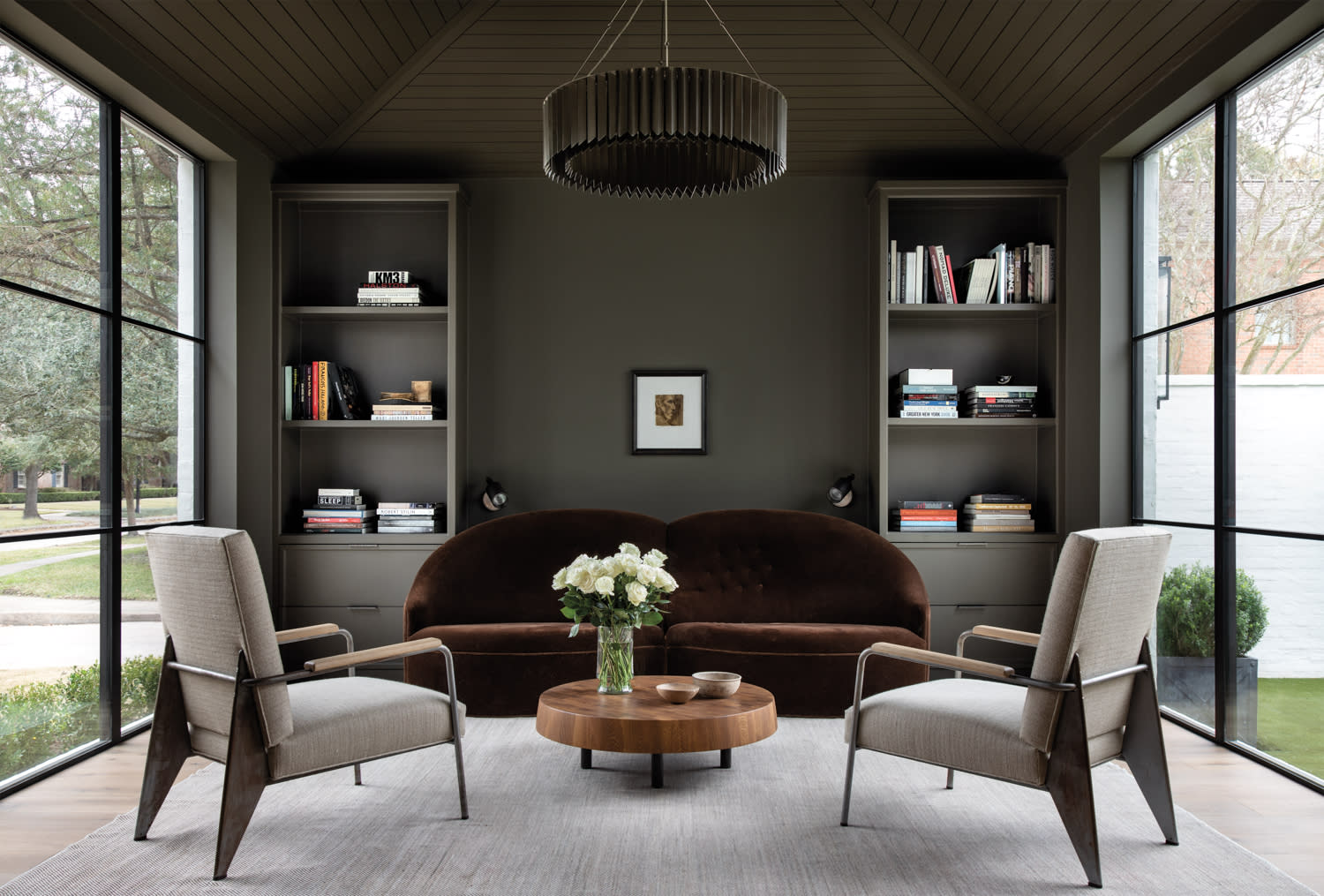 Black-painted study featuring dark moody walls and furnishings, open shelves with books and coffee table