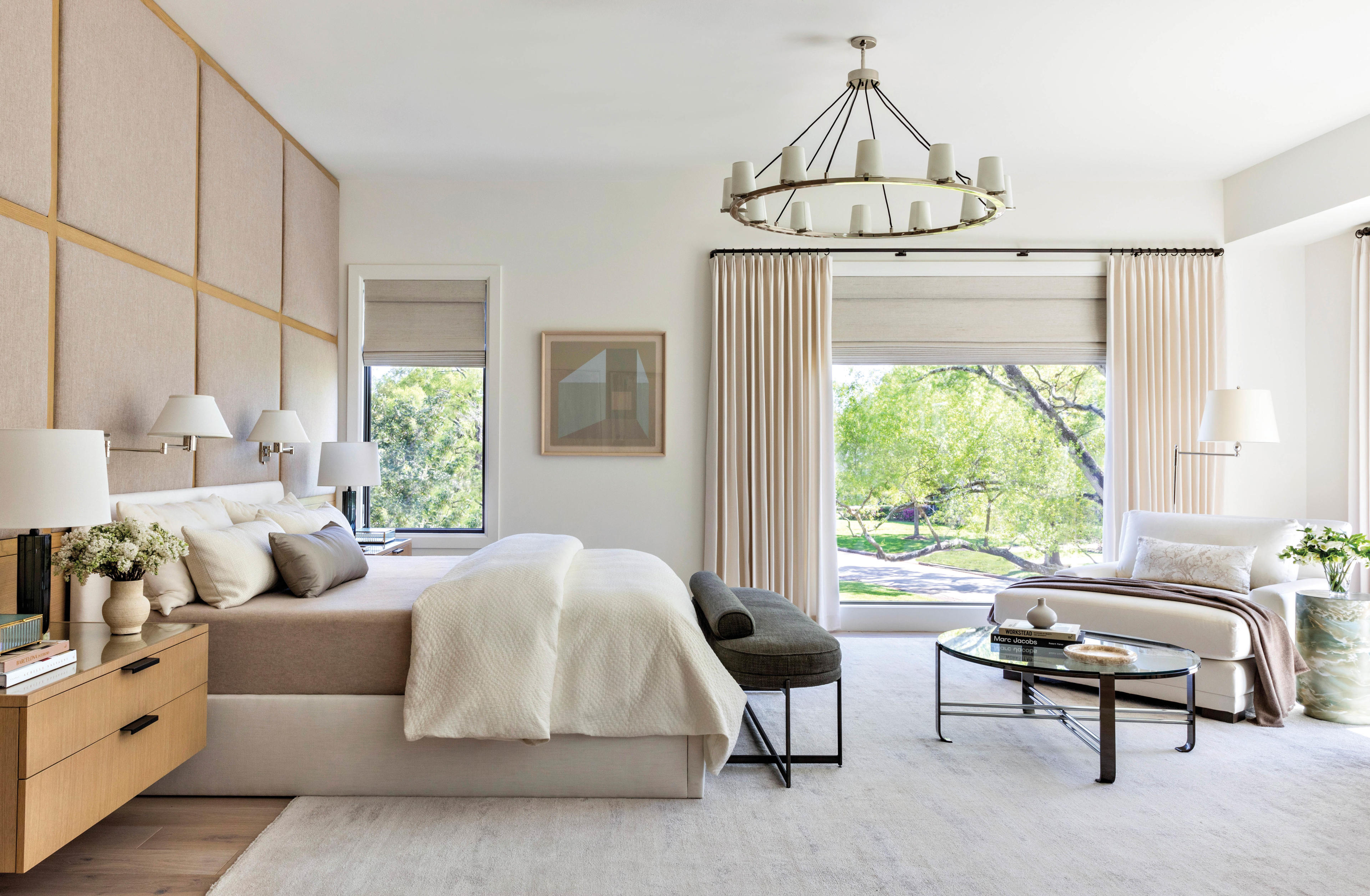 primary bedroom with bed, chaise and windows flanked by drapes