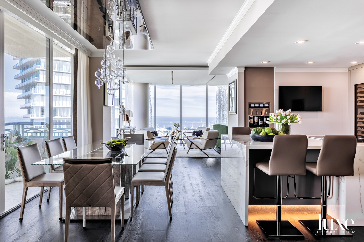 dining area with gray chairs, shiny long table and glass bulb chandelier