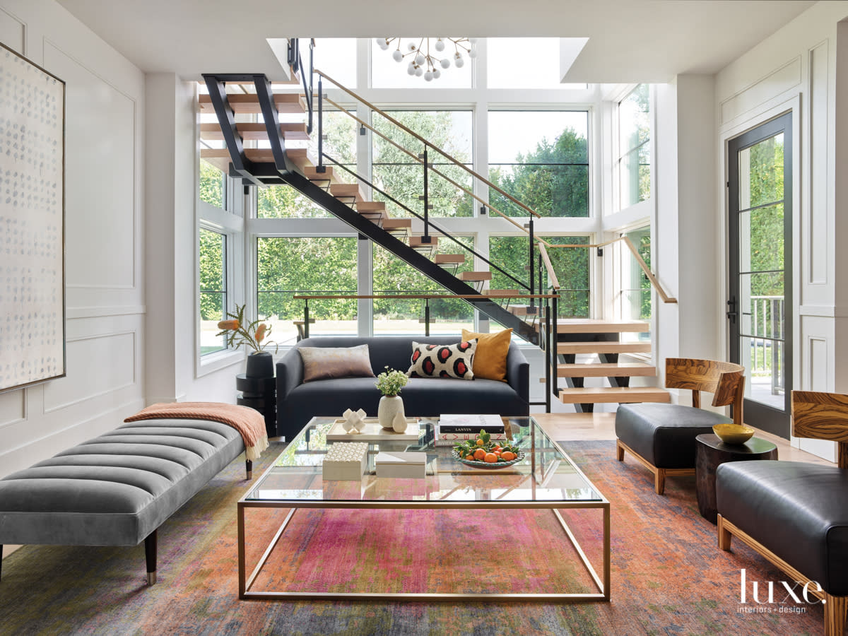 living room with staircase, pink and orange rug and floor to ceiling windows