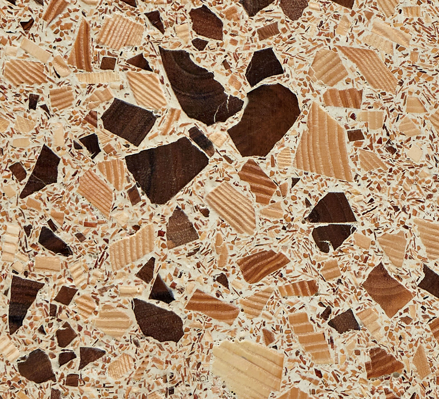 A terrazzo tile with geometric shapes in solid and patterned shades of brown on a white base.