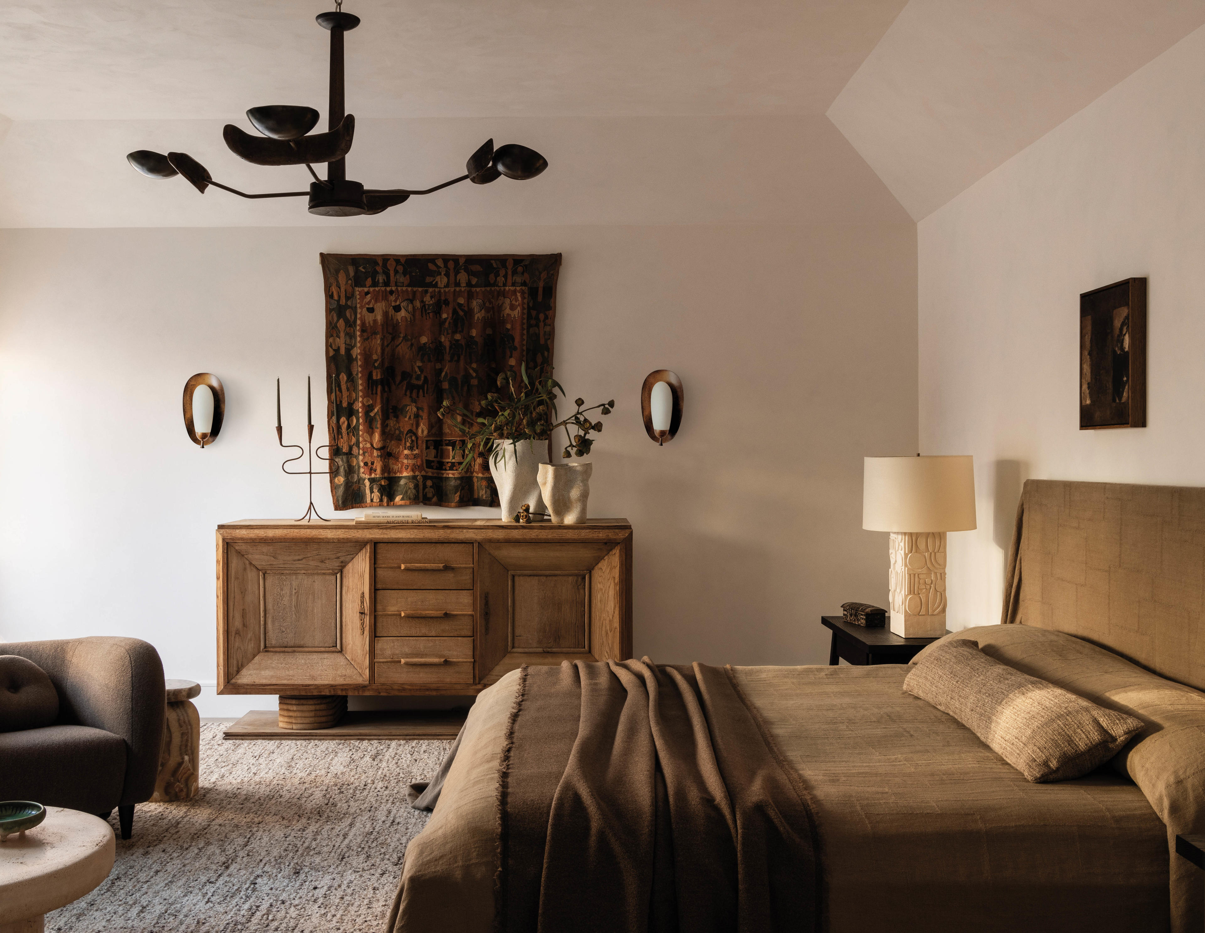 neutral bedroom with a moody tapestry above a vintage French dresser