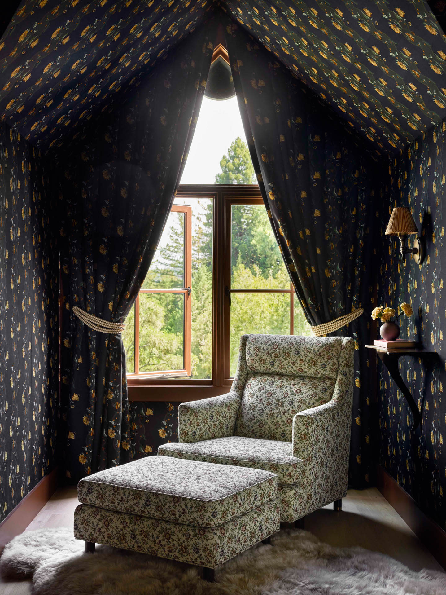 window seating area with a black and yellow floral wallpaper and a white and red floral armchair