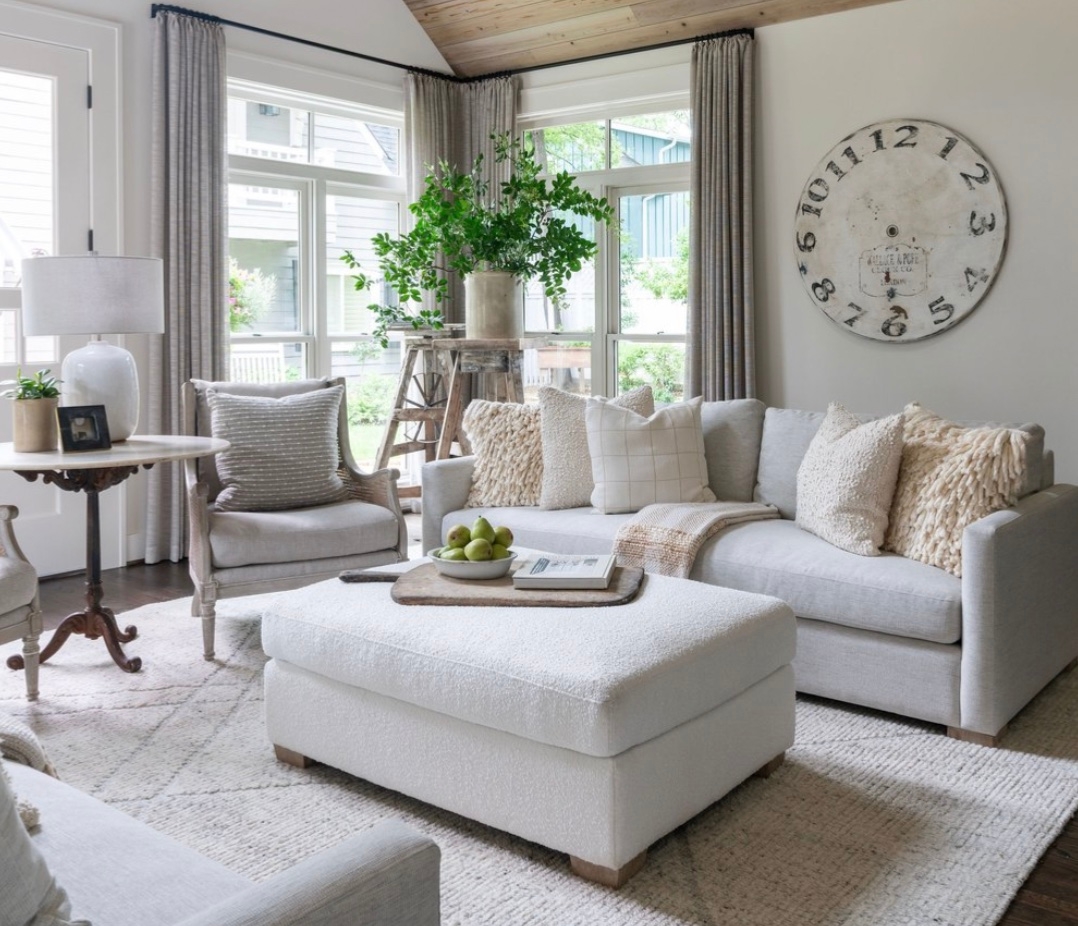 A living room with white furniture and a large clock.