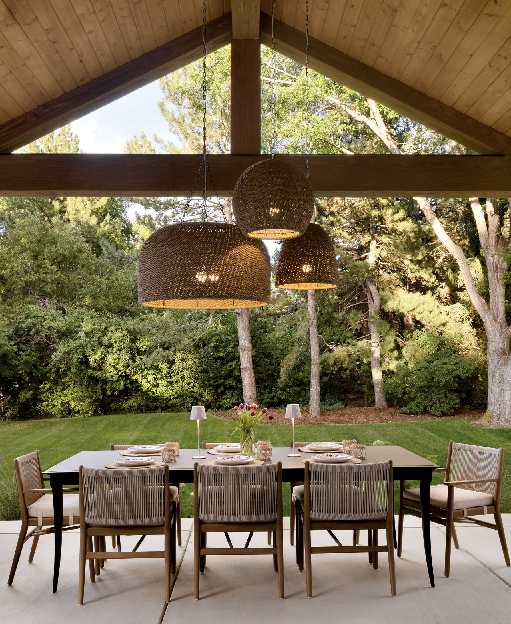 vaulted pine ceiling over an outdoor dining pavilion with Palacek seagrass pendants