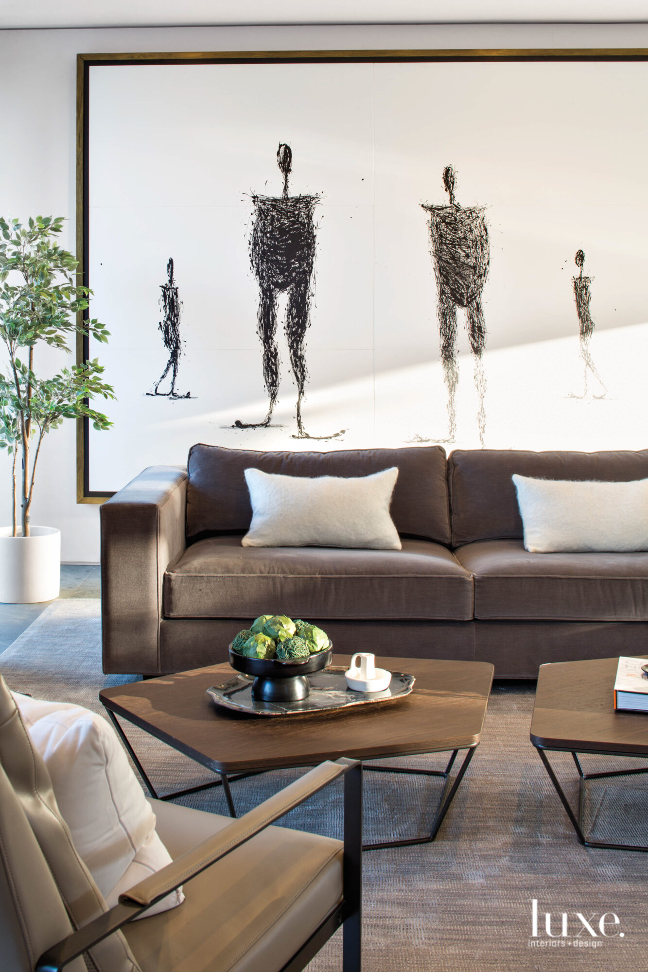 clean-lined living room detail with brown furniture, wood tables and figure painting in background