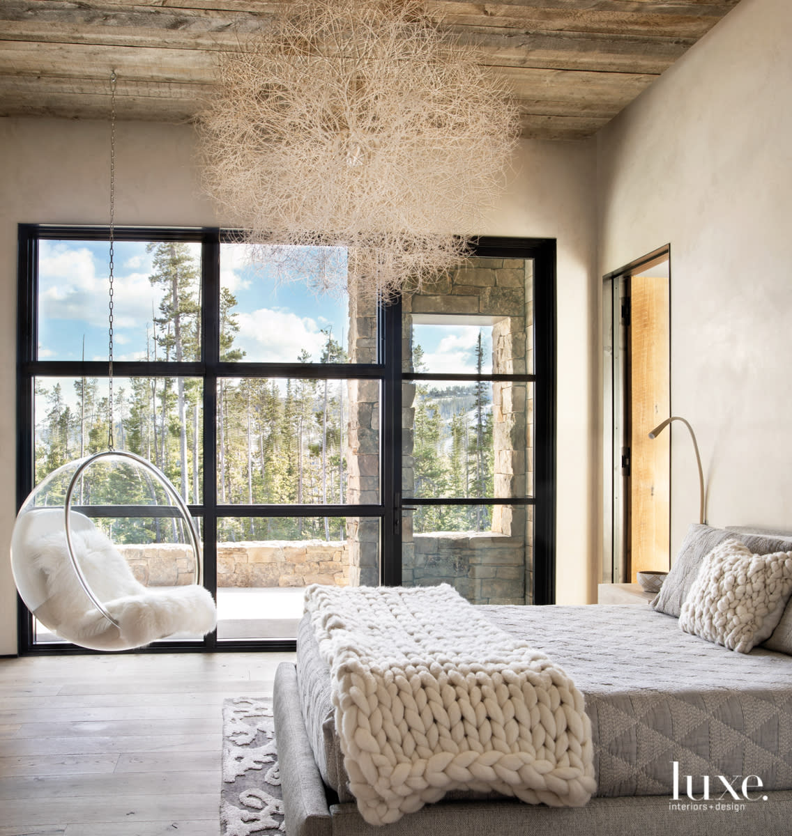 Guest bedroom with branch chandelier and swinging chair