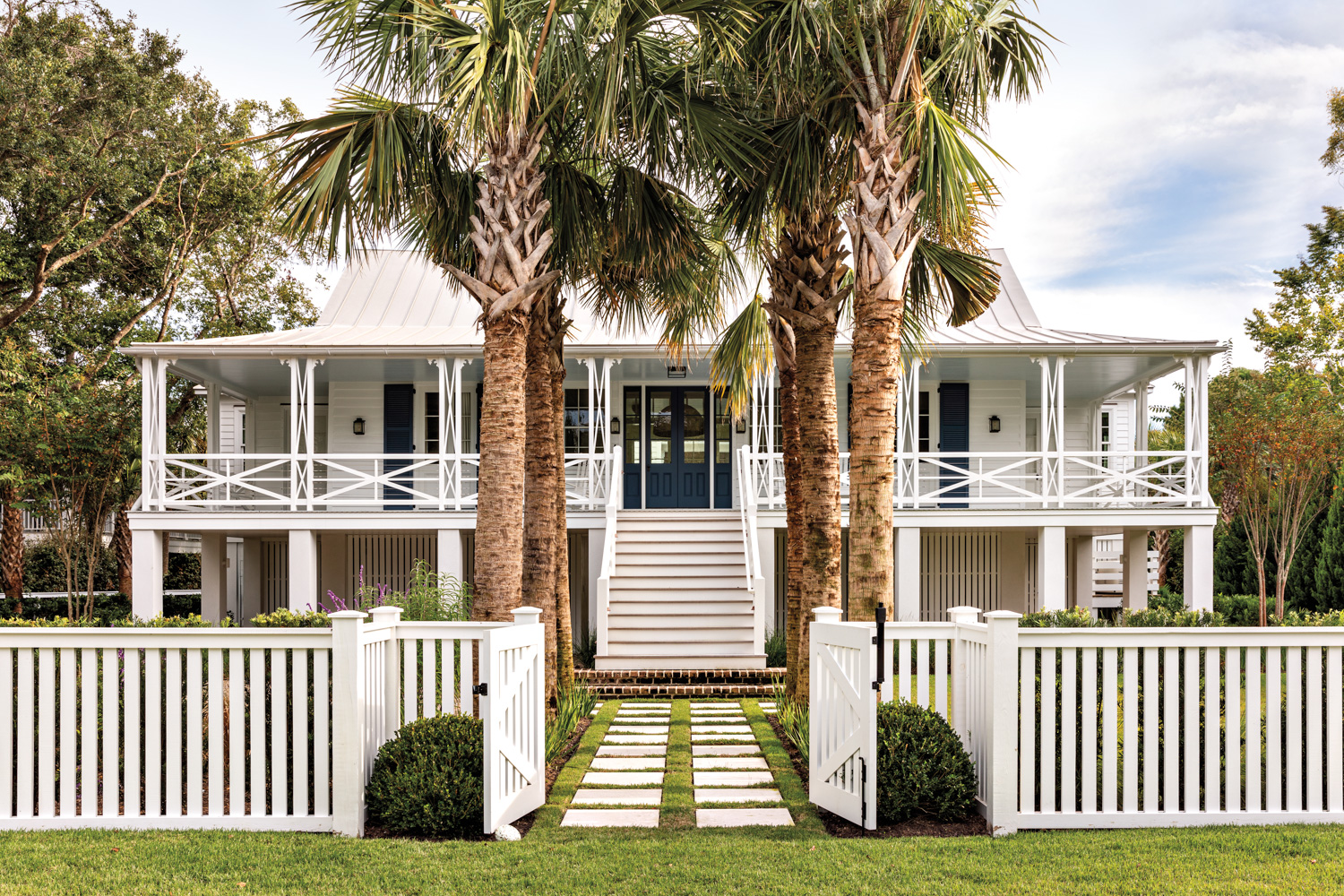 white house with picket fence, palmetto trees and two-story porch