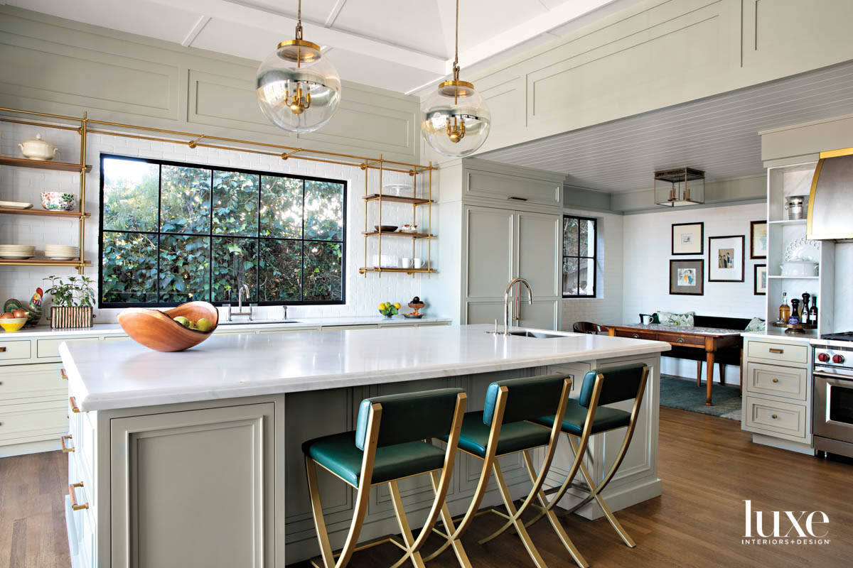 Kitchen with large island and two pendants hanging above. Small eating area in the background.