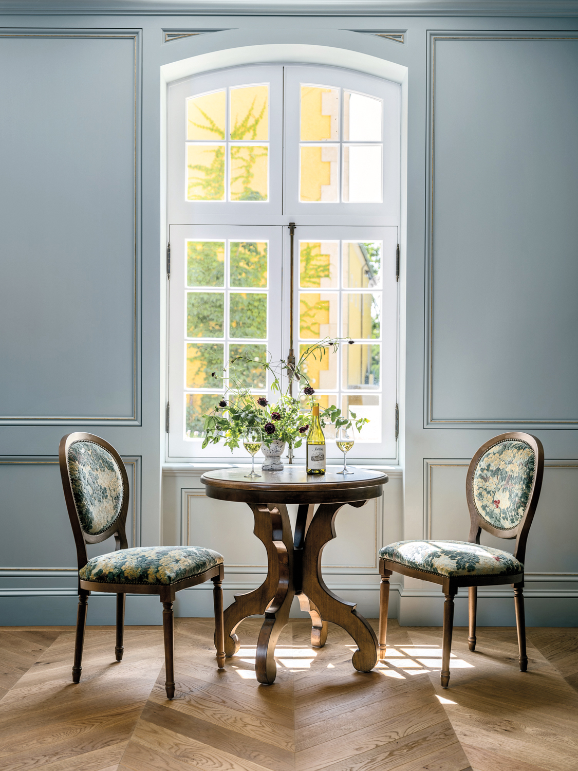 Jordan Winery with wood chairs and a round wood table set against a blue wall and a large window