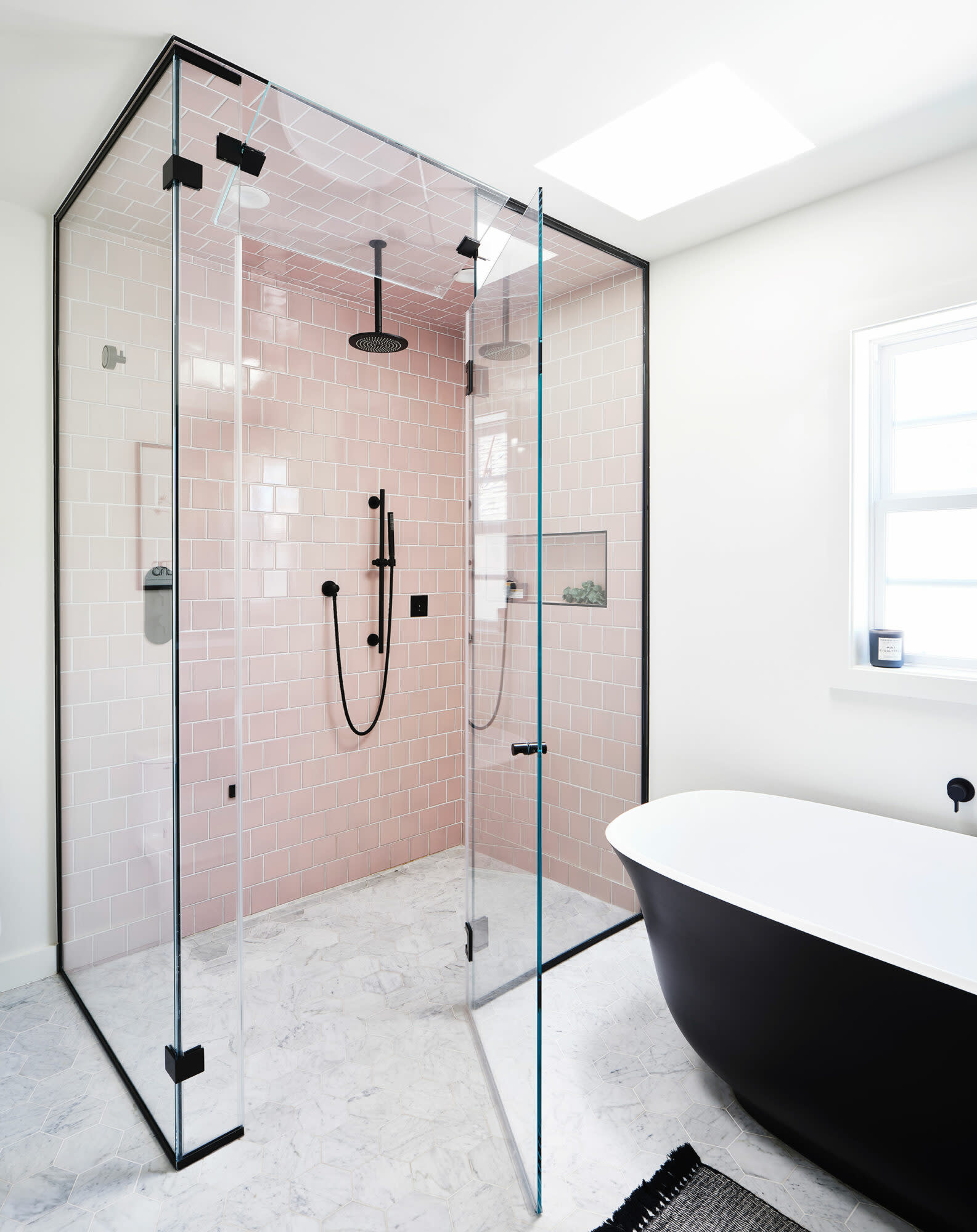 steam shower with pink tile and black freestanding tuh