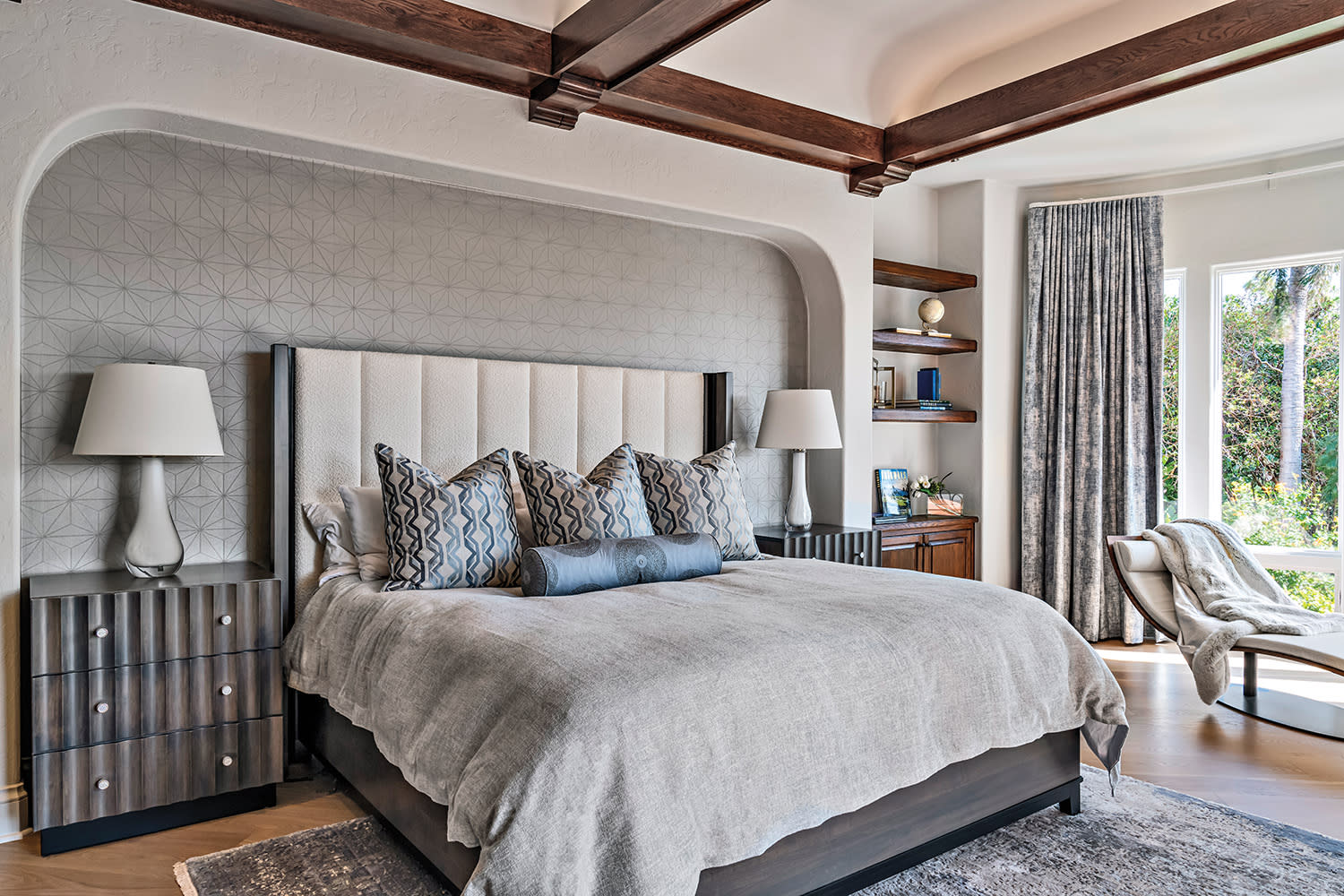 Elegant bedroom with a cozy bed adorned with patterned pillows and neutral linens, flanked by two modern lamps