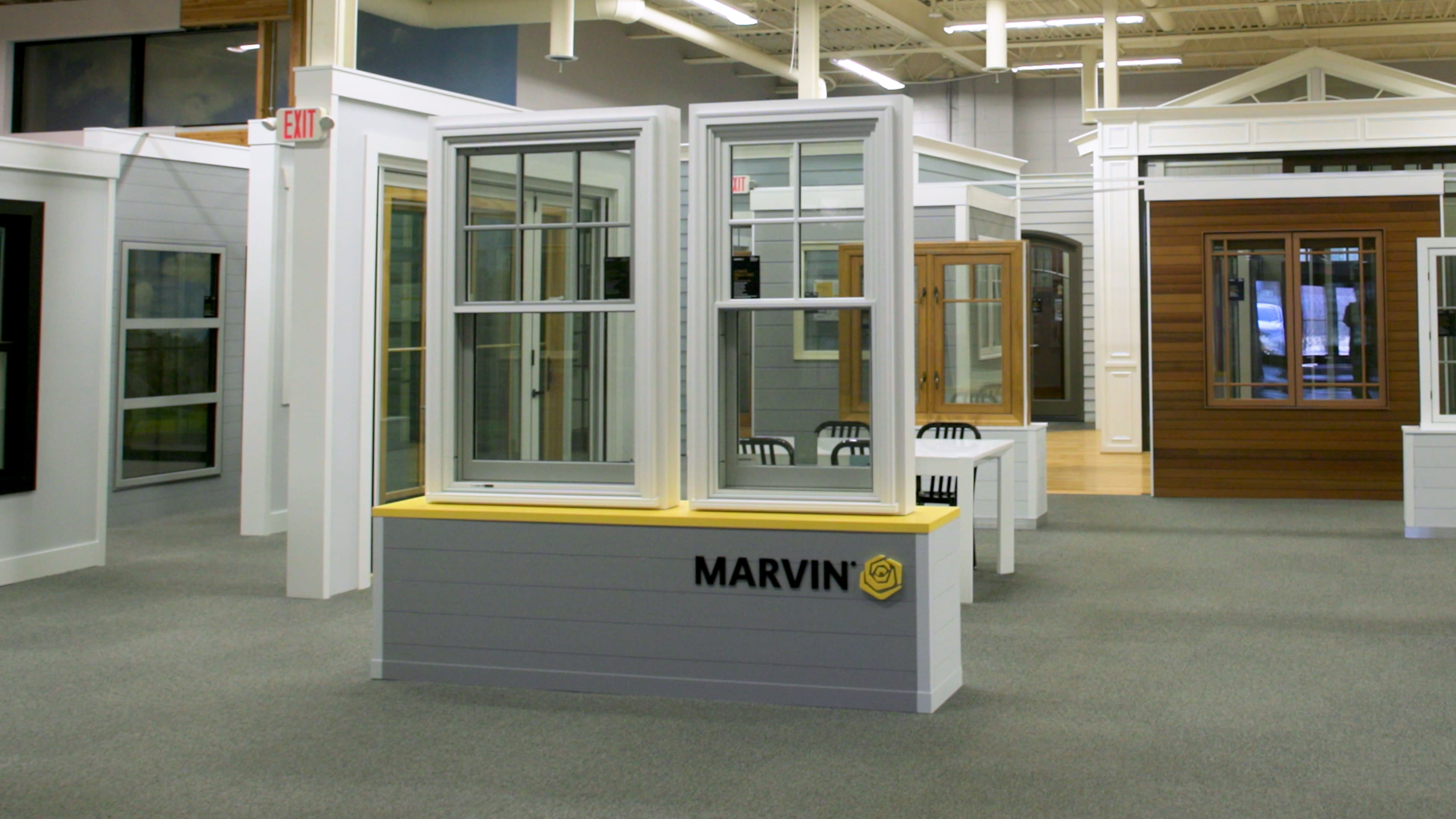 Showroom featuring Marvin windows with various styles and finishes displayed on stands. Bright lighting and a spacious layout convey a modern, inviting feel.