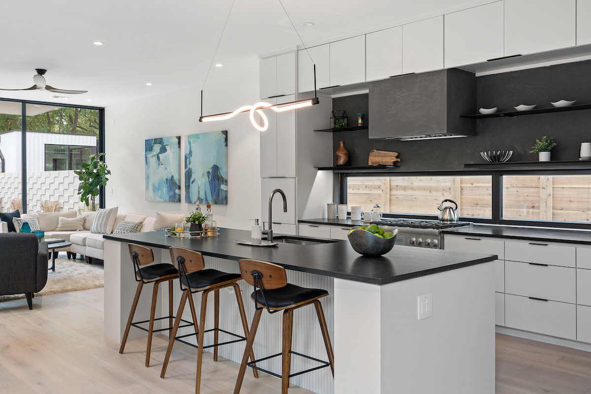 A contemporary kitchen with sleek black countertops and pristine white cabinets.