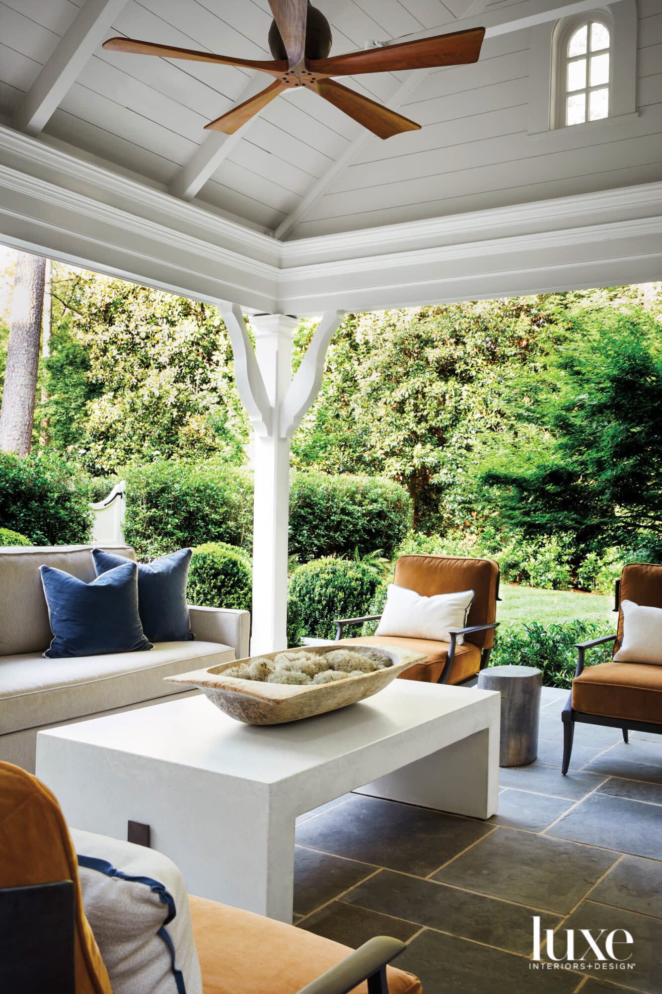 Covered outdoor entertaining area featuring plush, cognac-colored seating and modern white coffee table
