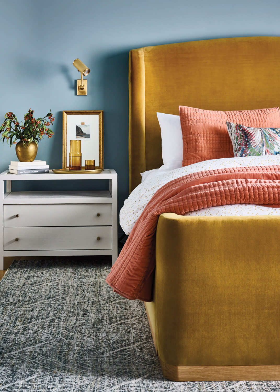 blue bedroom with a gold velvet upholstered bed and a white nightstand