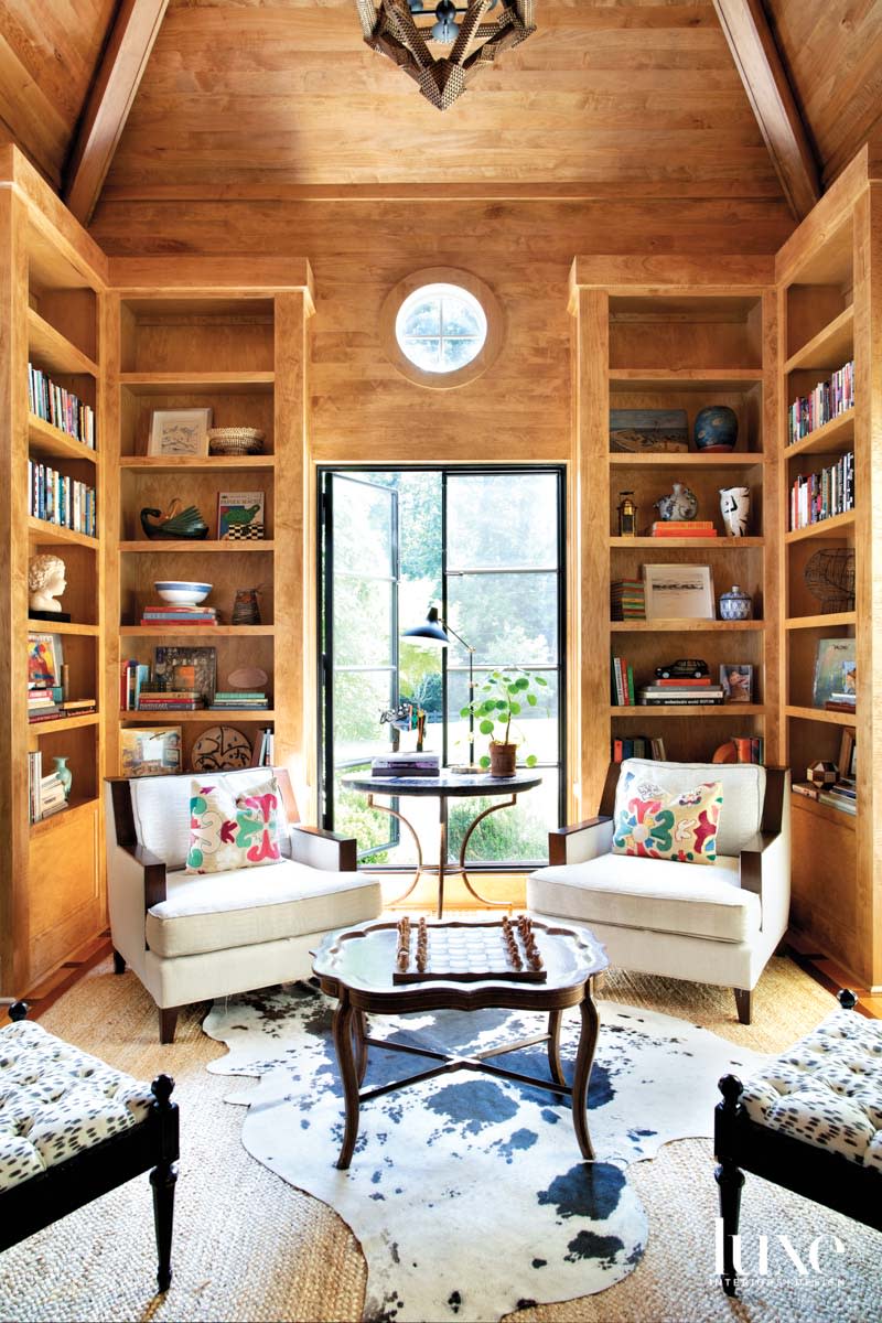Wood paneled library with round window and seating group