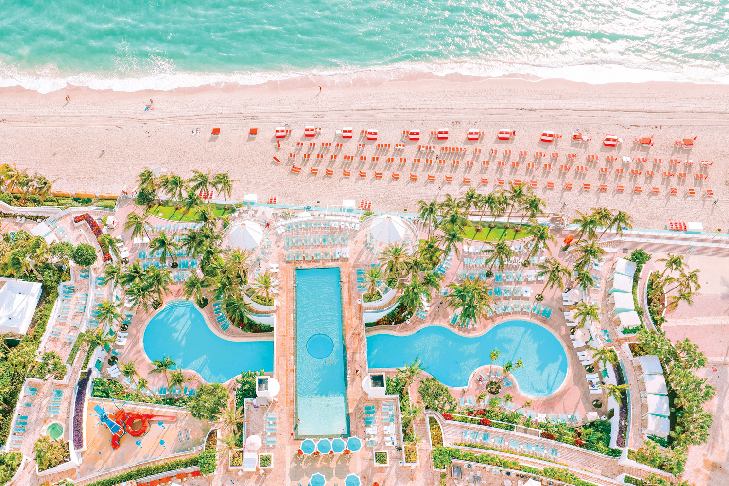 aerial view of Diplomat Beach Resort with a perpendicular lagoon and surrounding palms and greenery