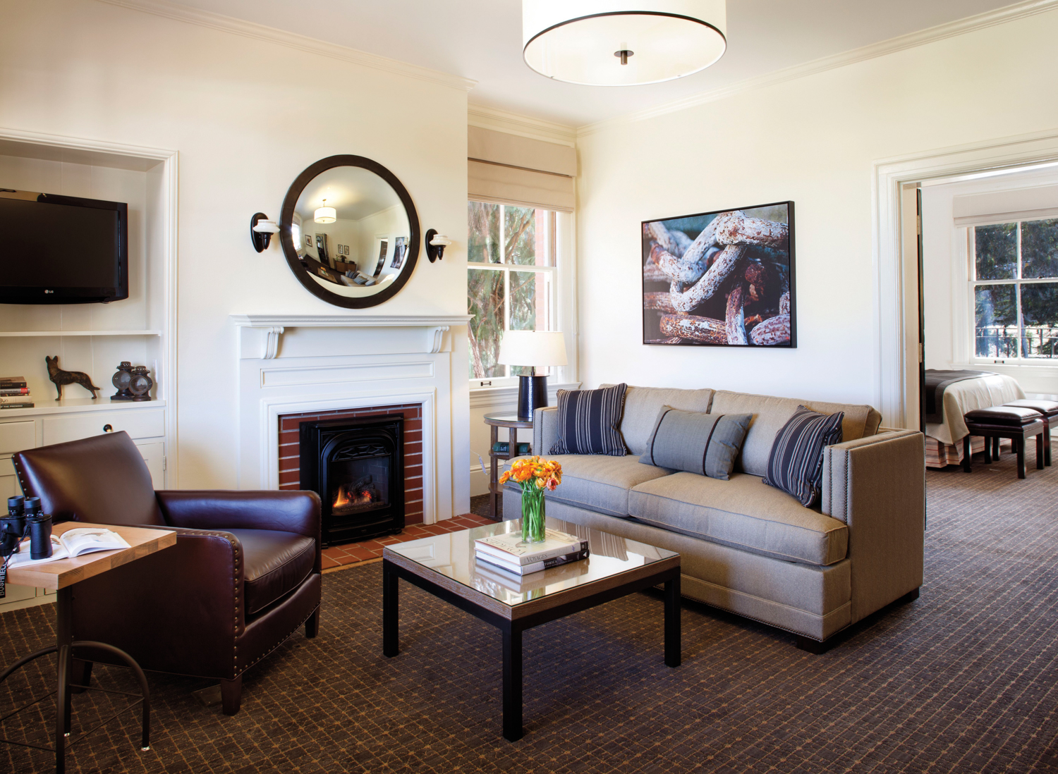 Sitting area next to fireplace with gray sofa, square coffee table and leather armchair.