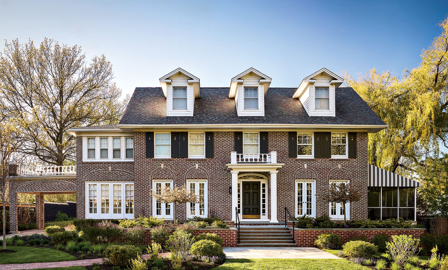 A large, two-story brick house with three dormer windows and a porch