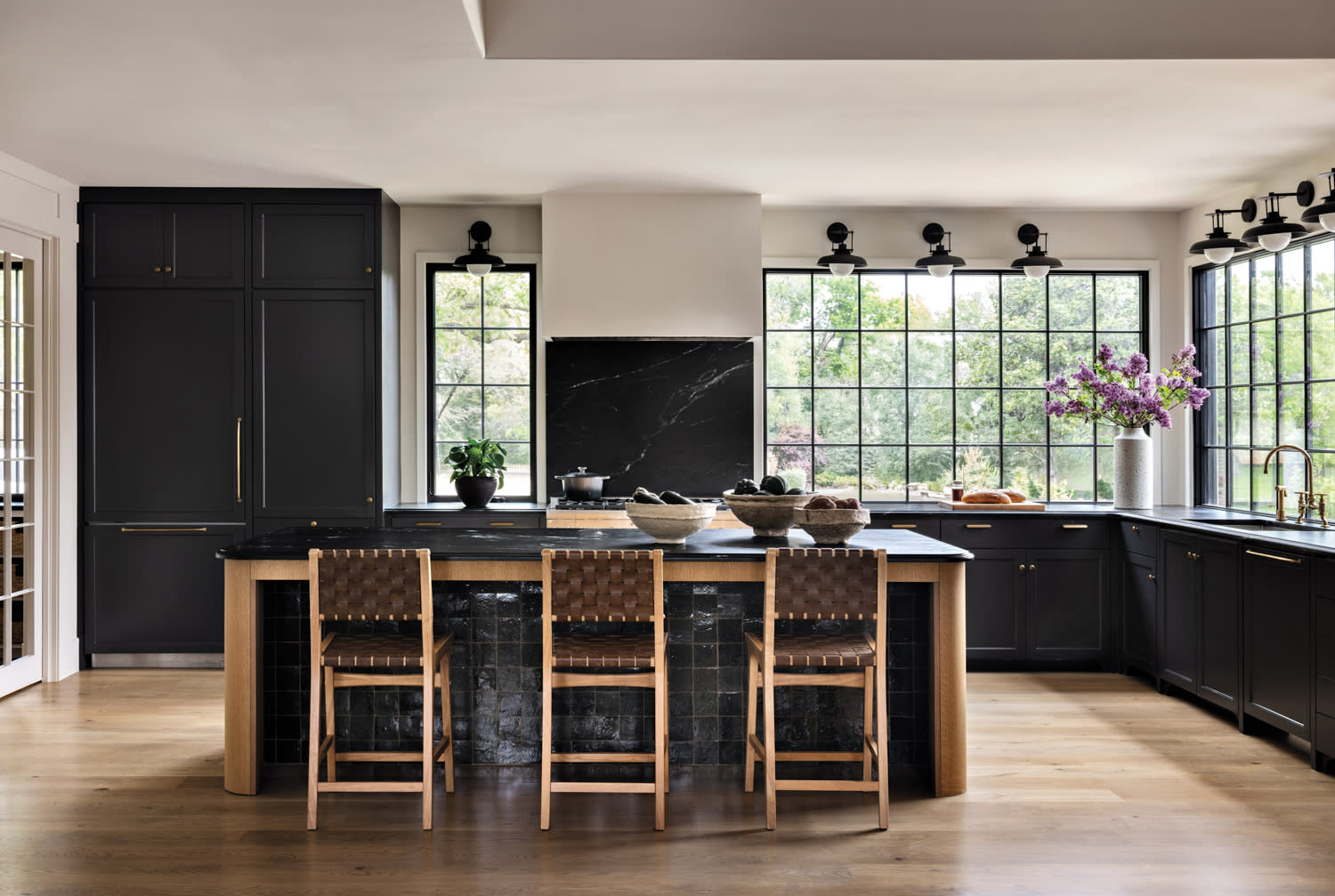 A kitchen with soapstone countertops, wide-plank white oak doors and leather-and-oak counter stools.