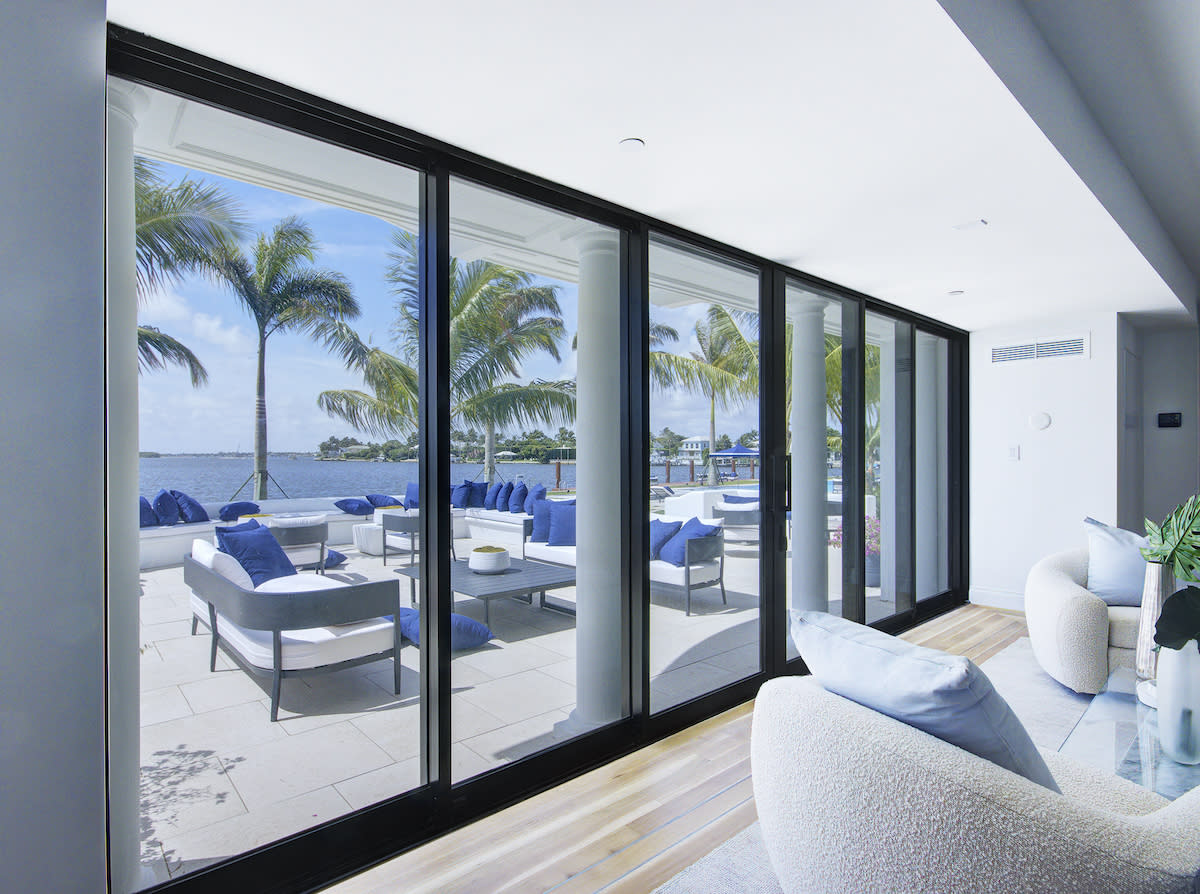 A spacious living room with expansive windows offering a scenic view of the water.