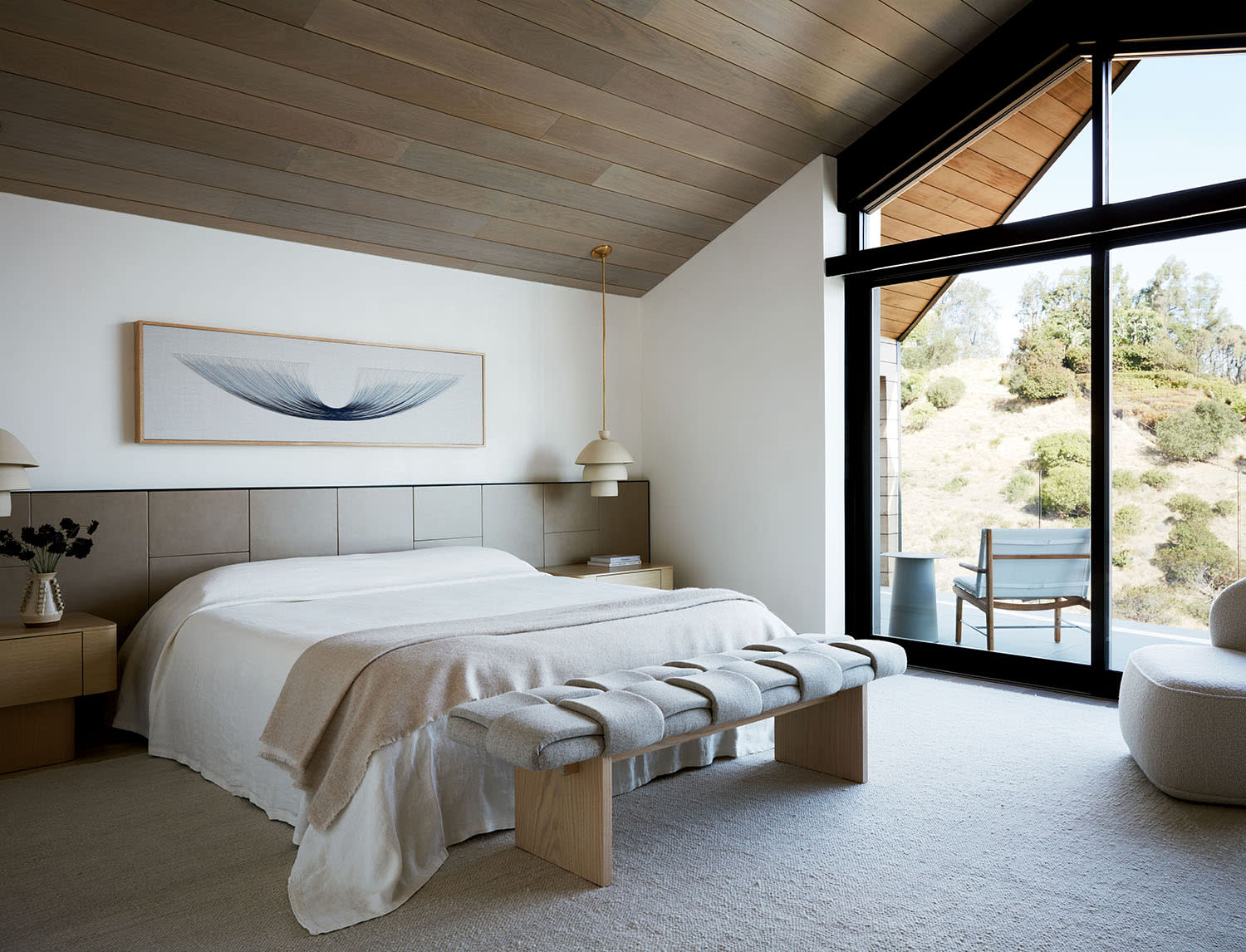 contemporary bedroom with a leather headboard and large windows