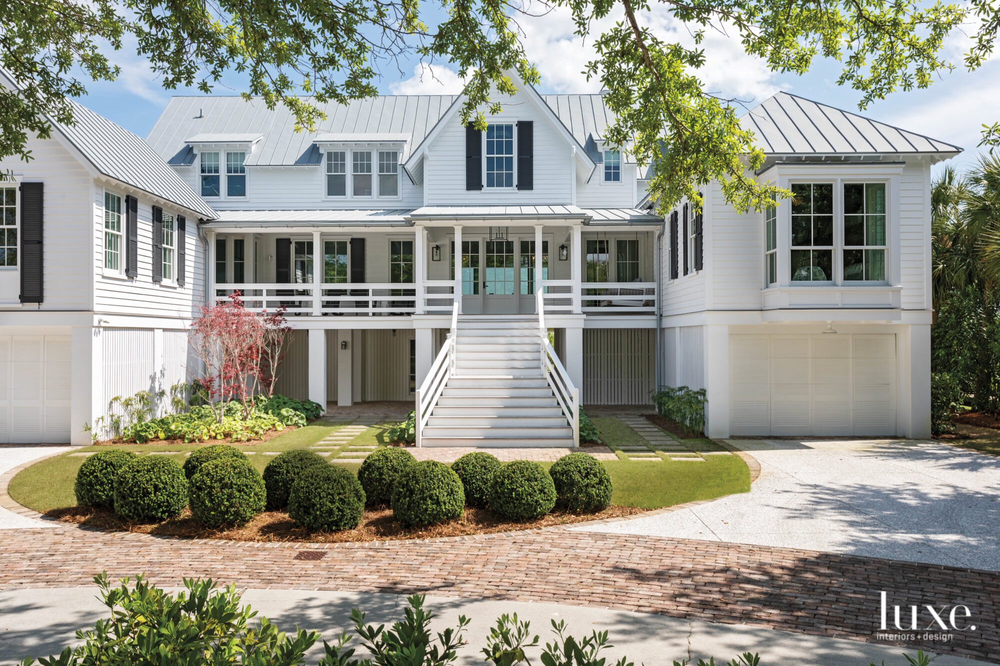 White house with wide porch, clipped boxwoods