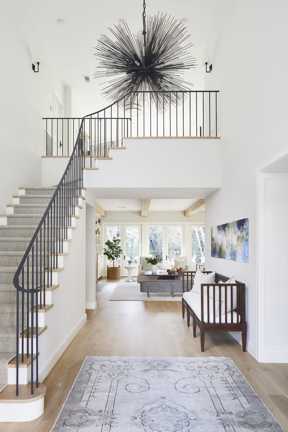 Dramatic entry way with bold chandelier and modern staircase. 