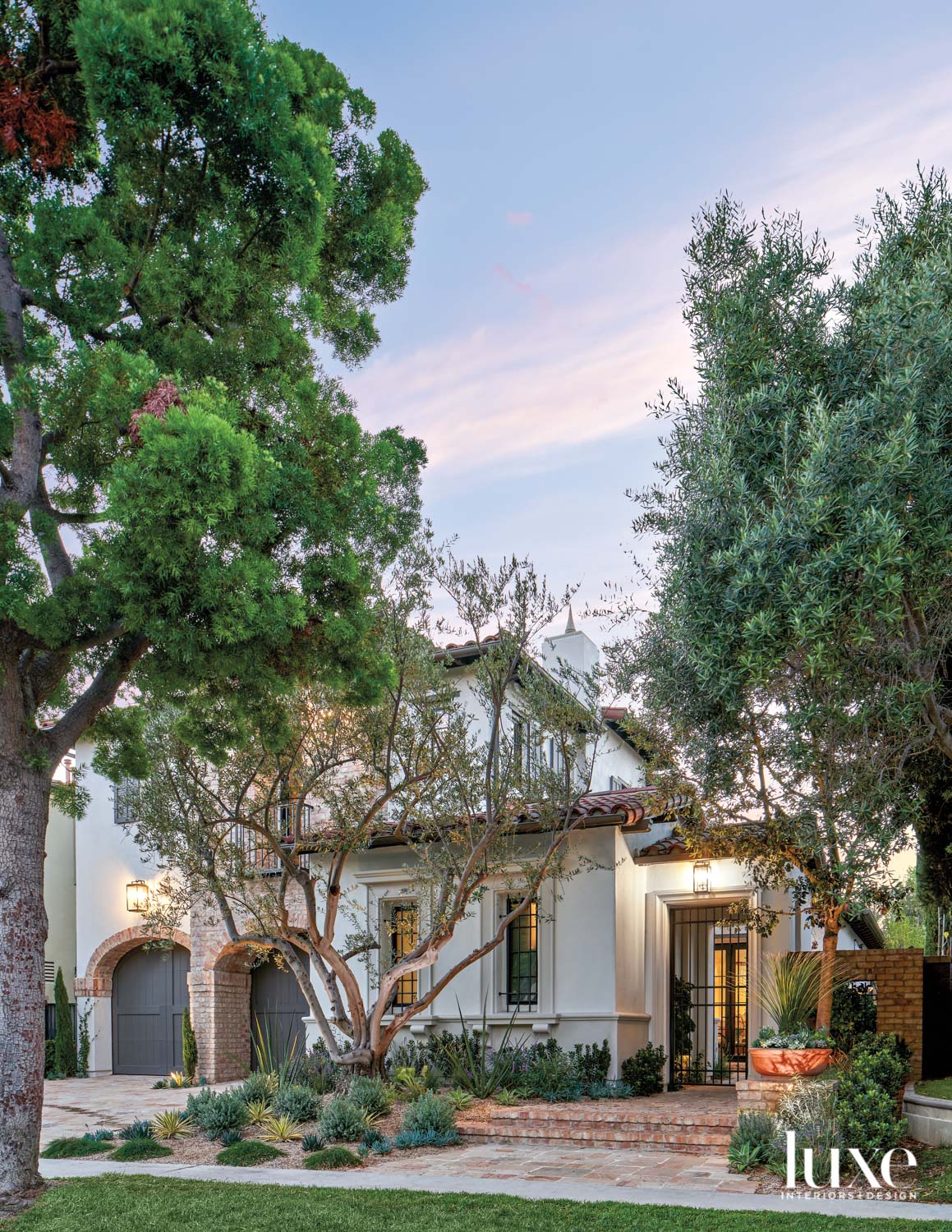 facade of tuscan style home with decorative metal grilles on windows and door with trees in the foreground