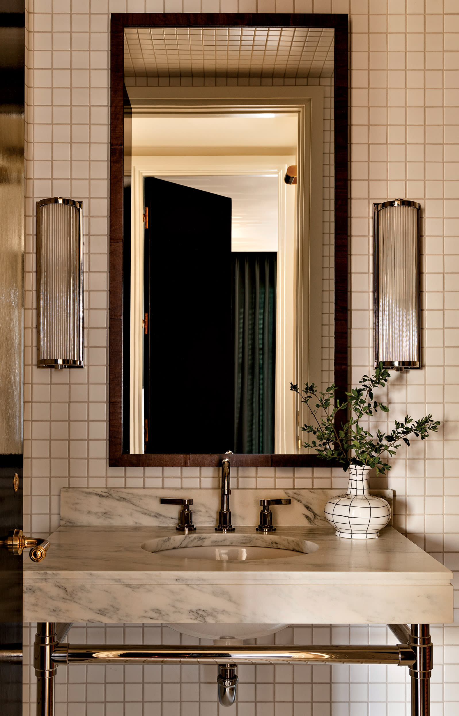 white ceramic tiles in a windowpane pattern line the walls of a guest bathroom 