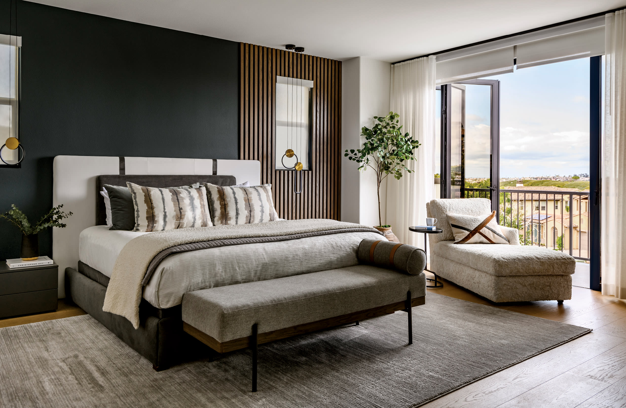 moody bedroom with a slatted oak panel on the wall and doors open to a sunny patio