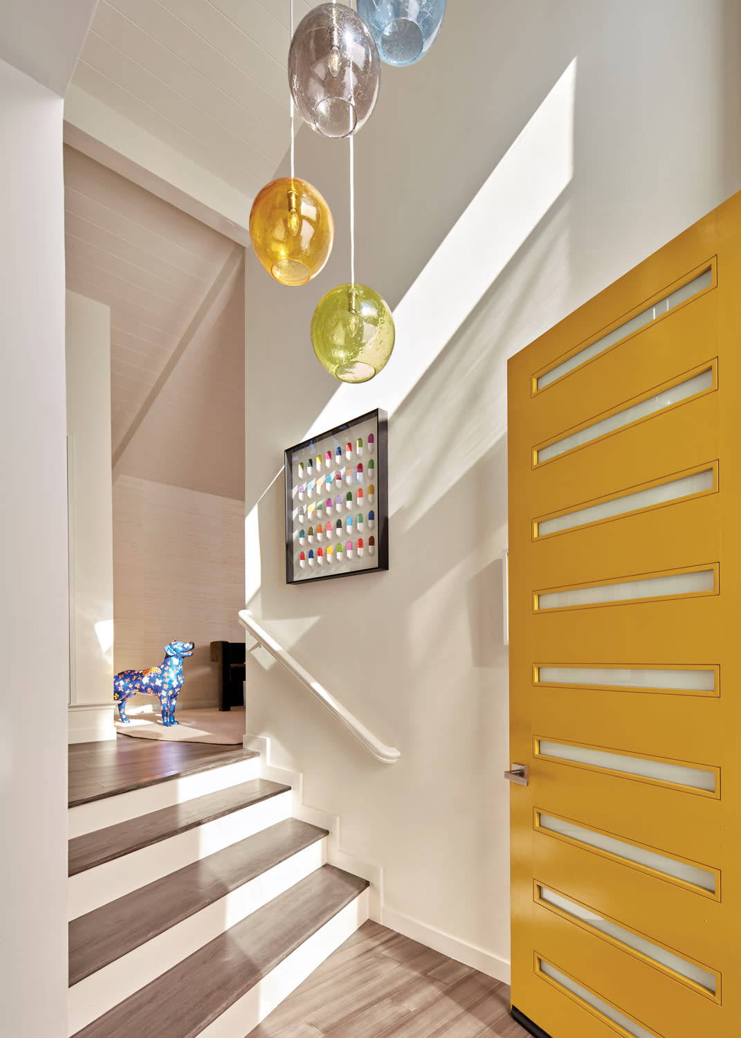 yellow front door opening to a colorful light fixture in a home's entryway